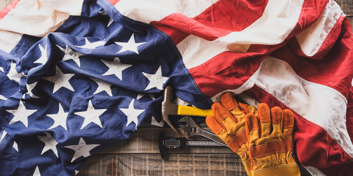 Happy Labor day concept. American flag with different construction tools on dark wooden background.