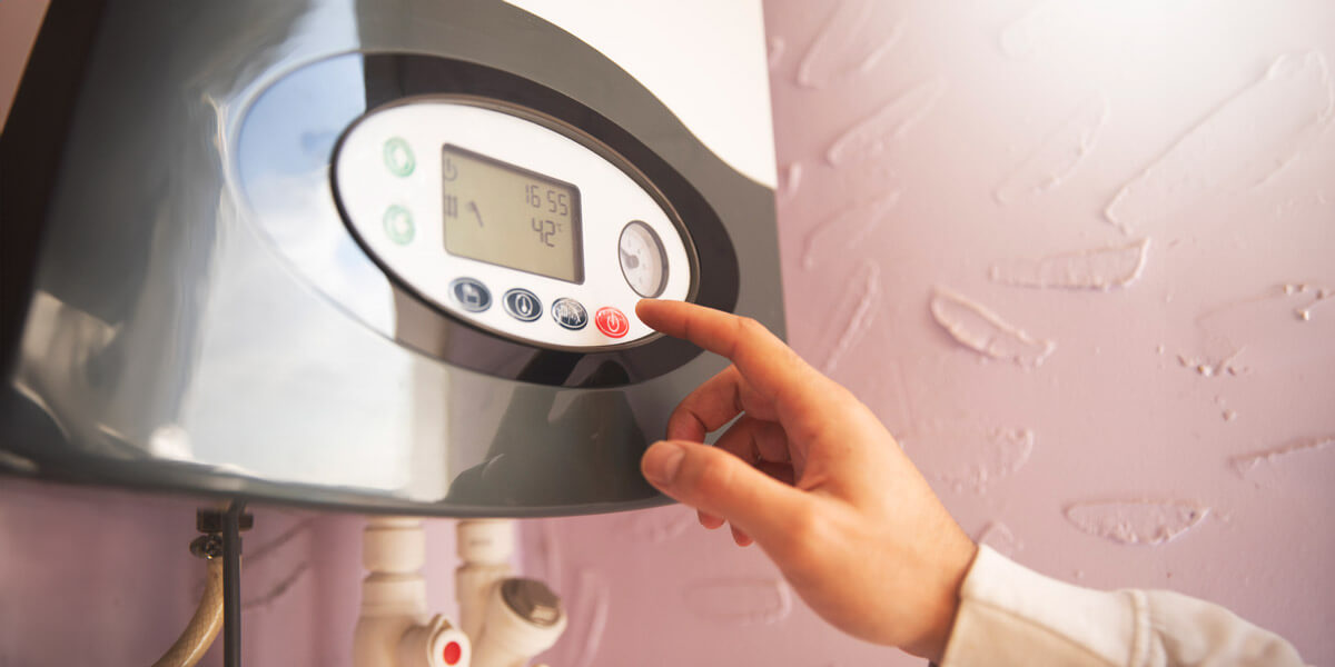 A person adjusting the control panel of a water heater.