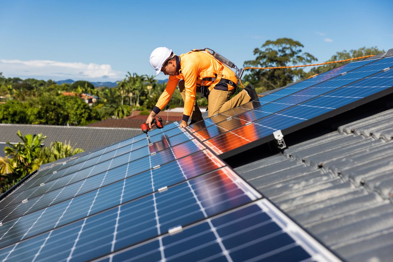 Solar panel technician with drill installing solar panels