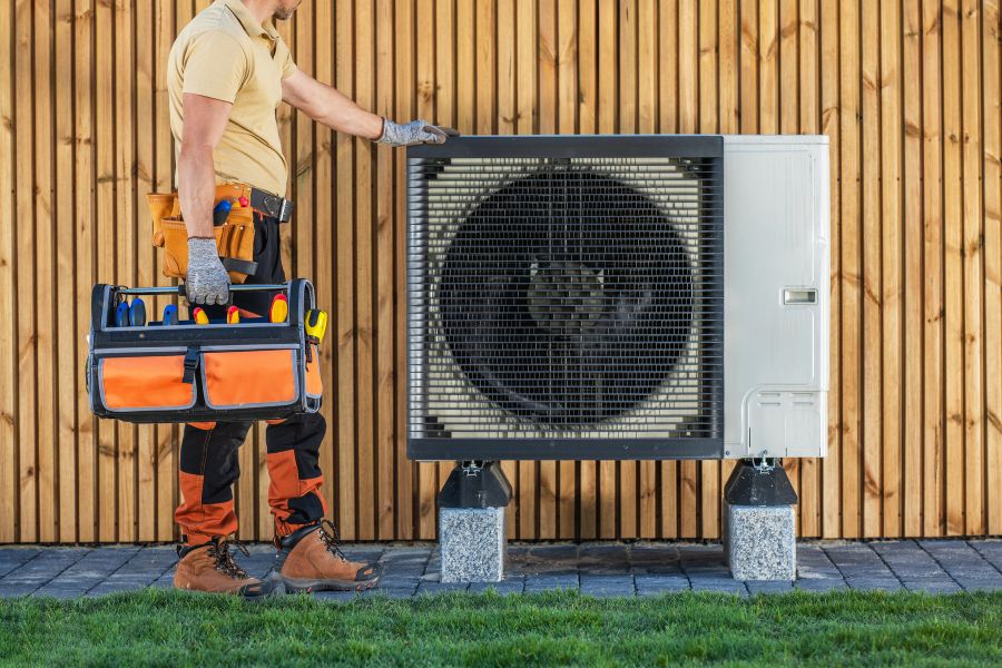 HVAC technician standing by air conditioning unit preparing for maintenance