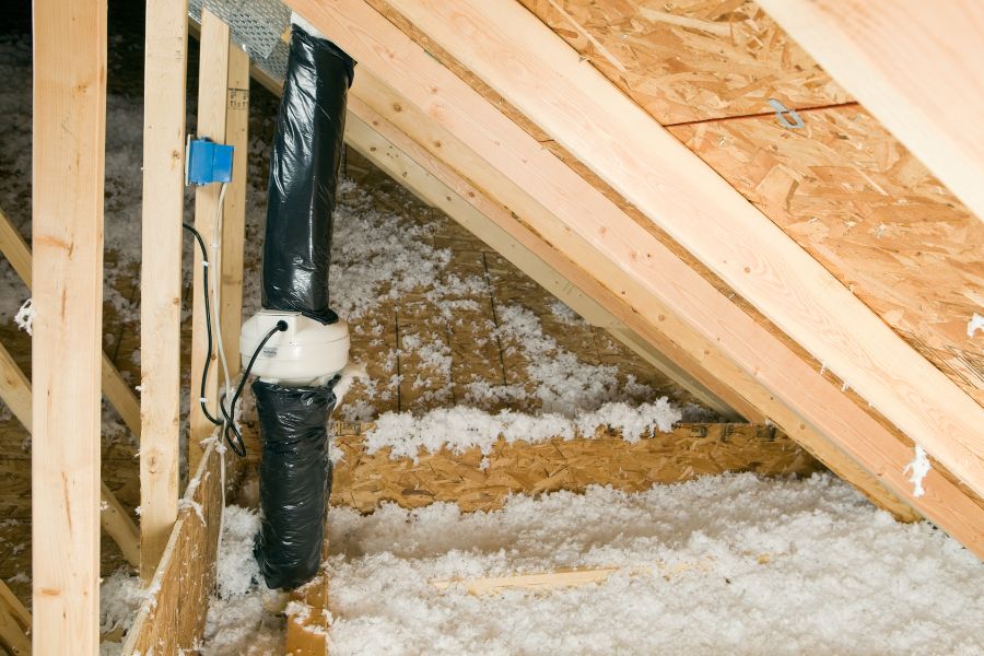 Attic radon vent fan with roof trusses and insulation