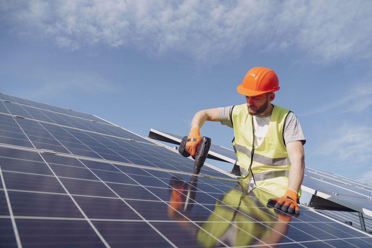 Solar panel technician with drill installing solar panels
